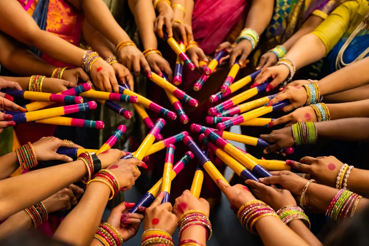 A colourful circle of hands holding Dandiya sticks